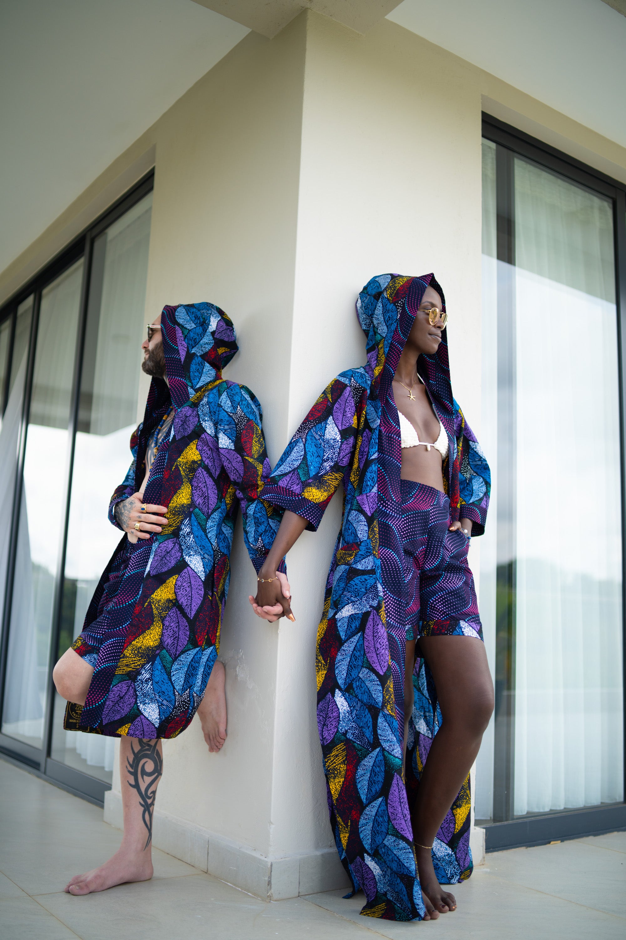 Interracial couple from zawadi hat fashion wearing colorful, patterned robes standing against each other