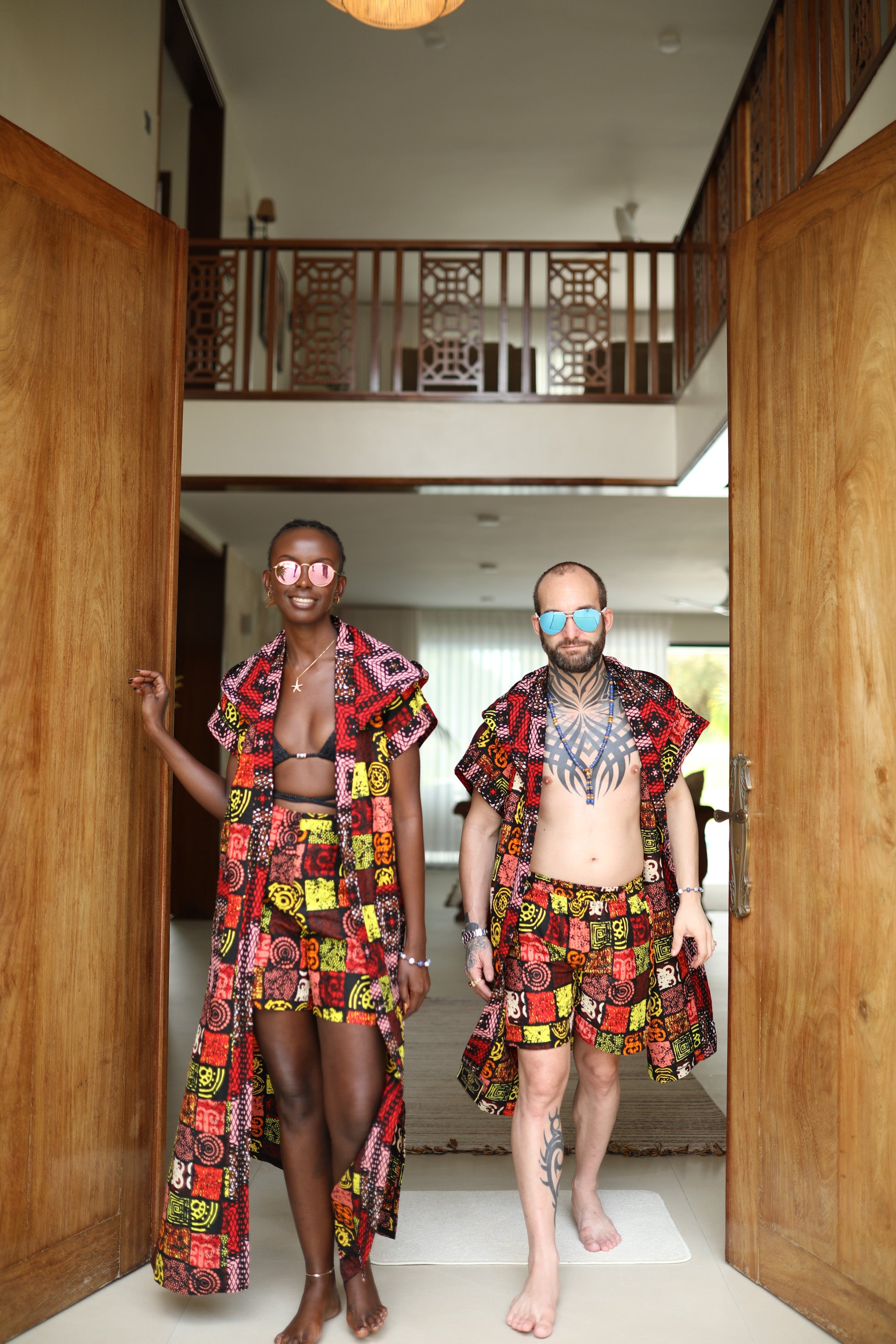 A couple styling Electric Safari African cover-up and shorts set in safari-inspired print – Zawadi Hat Fashion in a home setting.